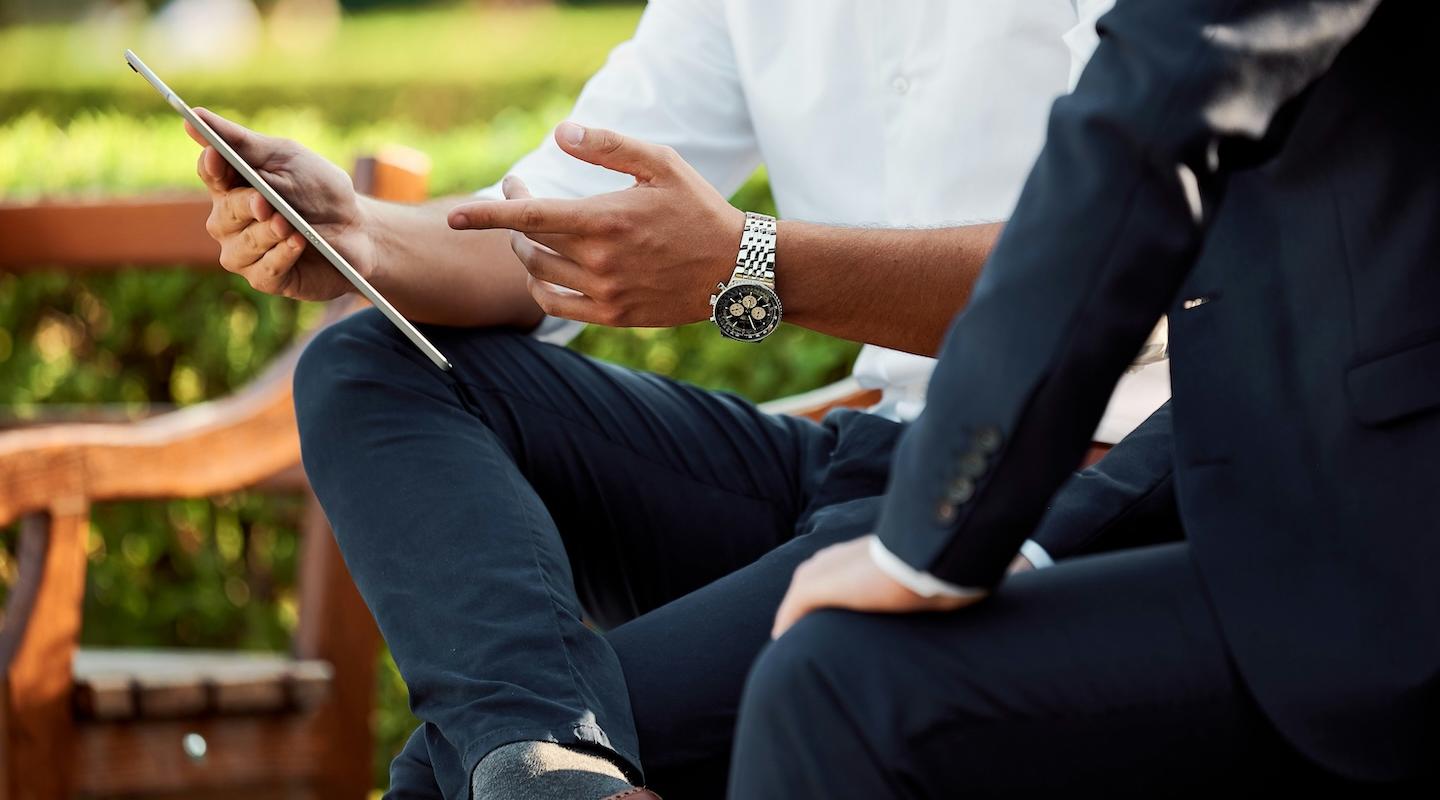 Man points at iPad while showing colleague