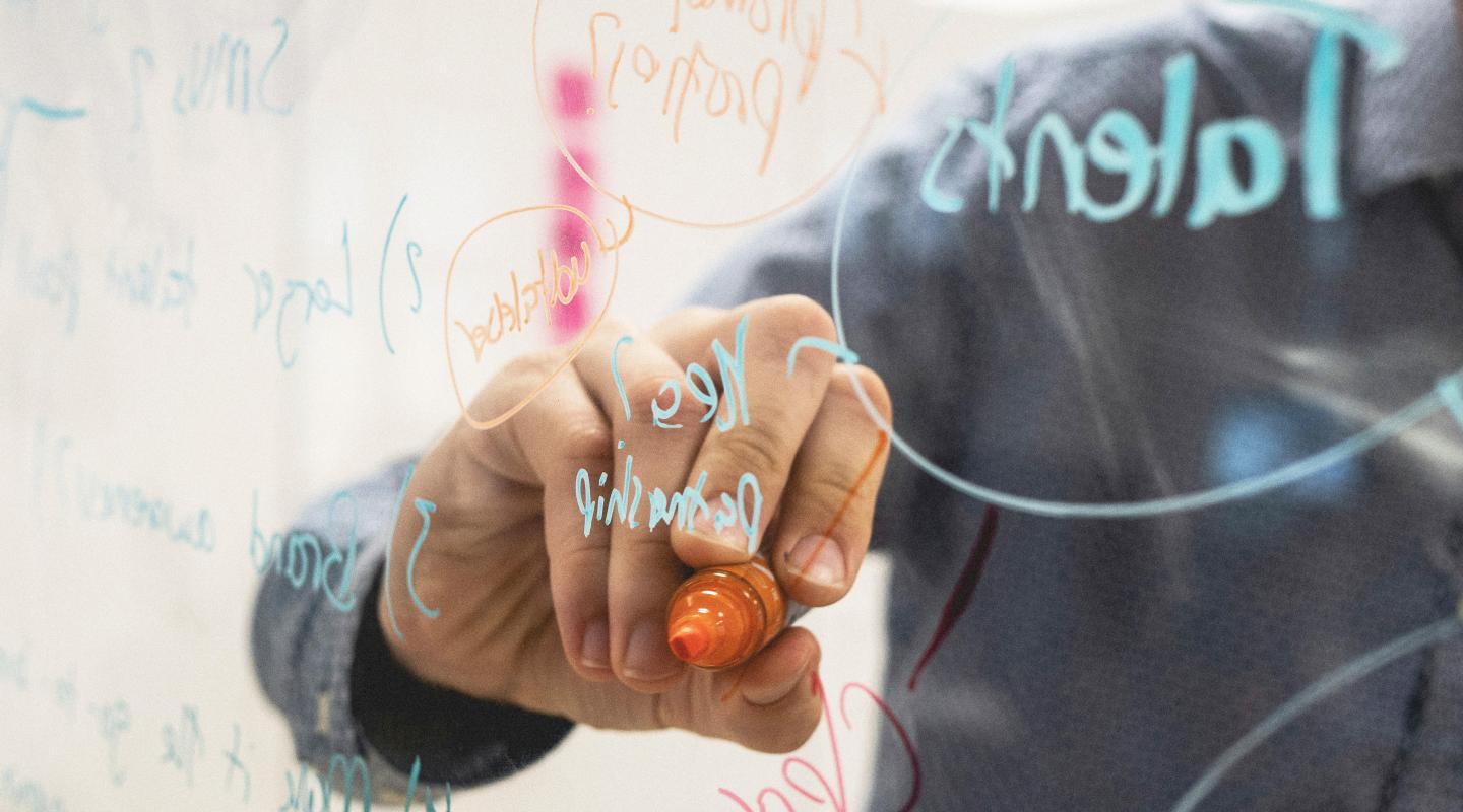 Person writing on transparent whiteboard
