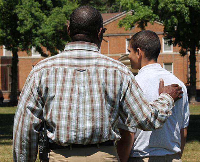 An Abraxas youth stands with an adult role model, who has his hand on the youth's shoulder in support