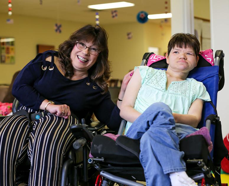 Two women in motorized wheelchairs at support center